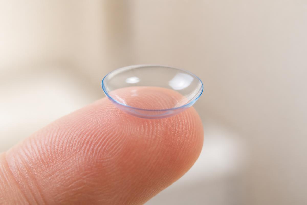 A soft contact lens balanced on a fingertip